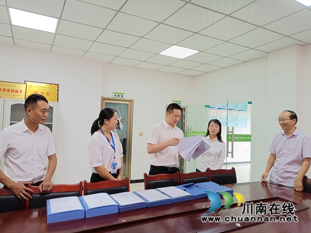泸州市江阳区农民工服务中心副主任章华新（左三）在泸县得胜镇现场查阅四川民鑫劳务专合社工作台账.jpg